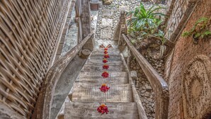 A narrow wooden staircase with a rustic design, flanked by stone walls and a small garden area with plants. - Santhiku Hotel & SPA (Banjar)