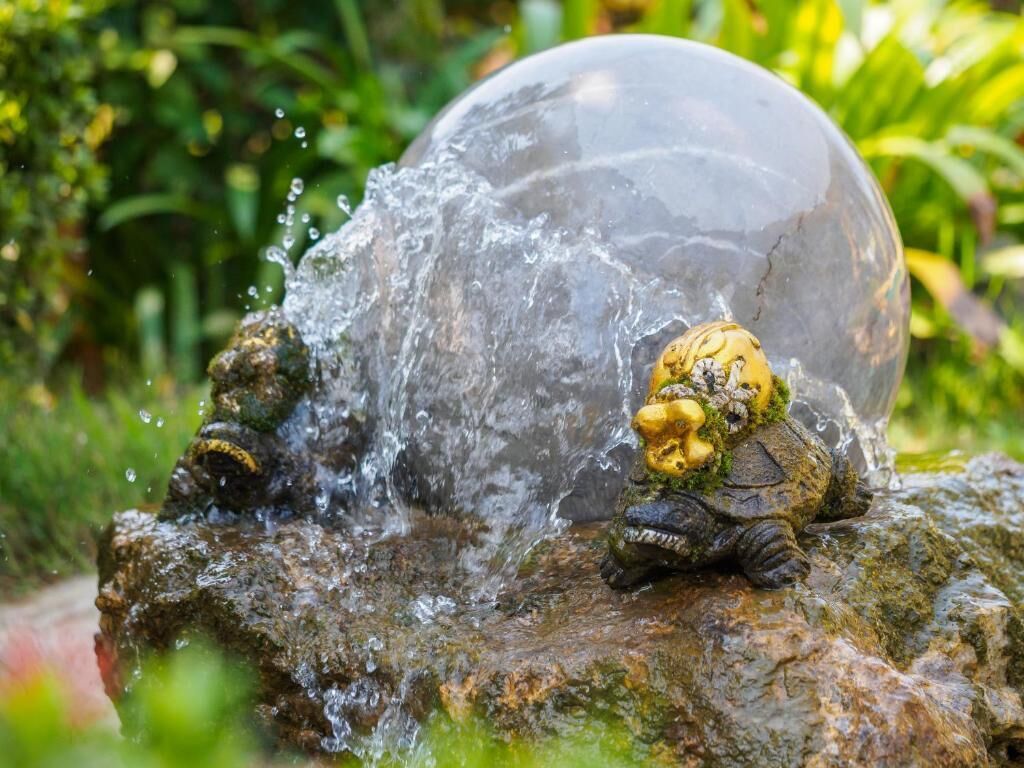 Una scultura di una tartaruga su una roccia, con l'acqua che schizza tutt'intorno.