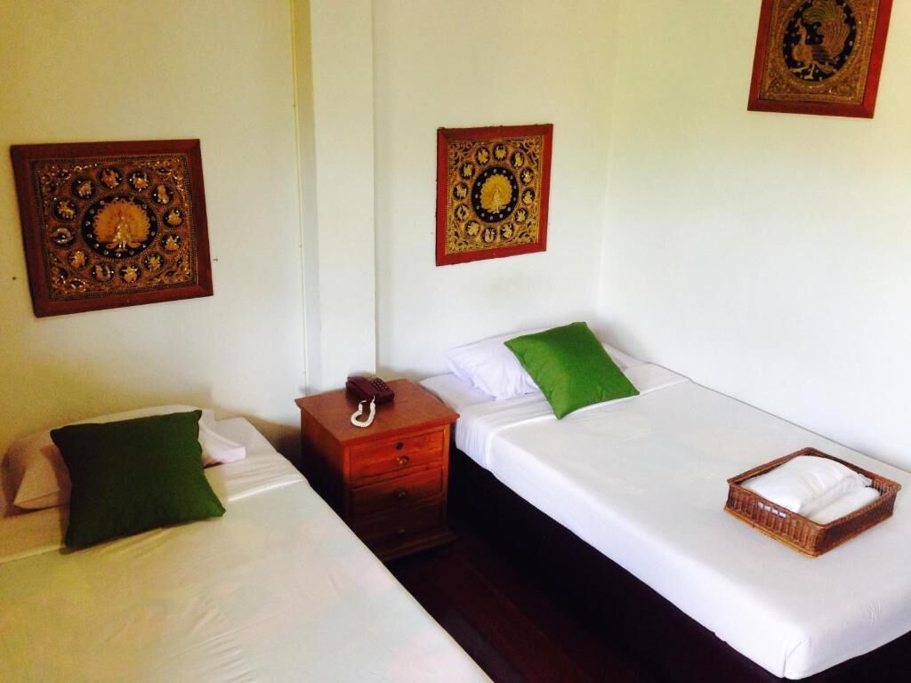 A hotel room with two single beds, each with a pillow and a bedside table.