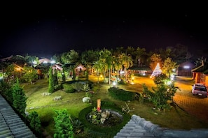 A nighttime view of a well-lit garden with pathways, palm trees, and a small pond. - ChiangsanGoldenland Resort 1 (Chiang Saen)