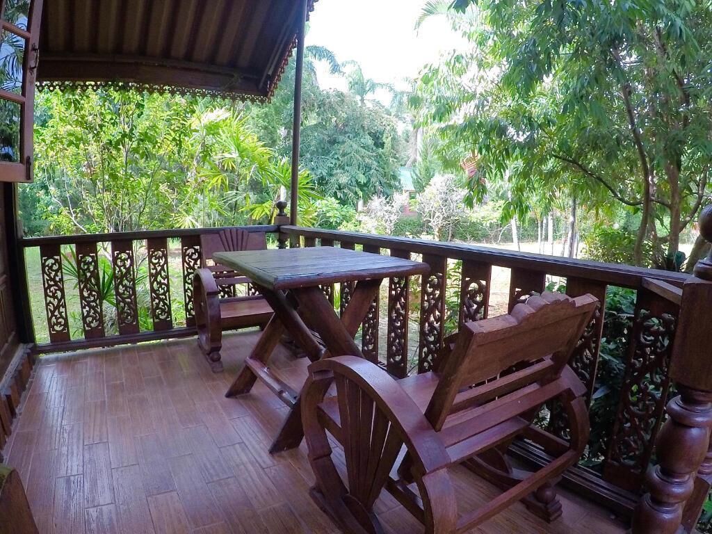 Une terrasse en bois avec une table et des chaises, entourée d’une balustrade décorative.