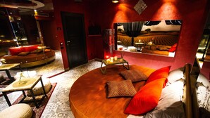 A circular bed with a wooden frame, red and white pillows, and a small table with candles.