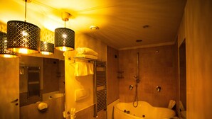 A bathroom with a bathtub, a sink, and a bidet. There are hanging lights and a towel rack.