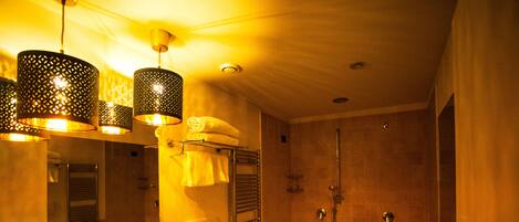 A bathroom with a bathtub, a sink, and a bidet. There are hanging lights and a towel rack.