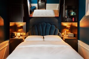 A hotel room with a bed, bedside tables, a nightstand, a mirror, and a shelf with various items. - Provocateur, Berlin, a part of Sircle Collection (Berlin)