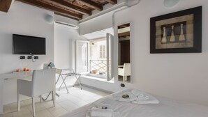 Una habitación de hotel moderna con una cama, un escritorio, una silla, un televisor y una ventana con vistas.