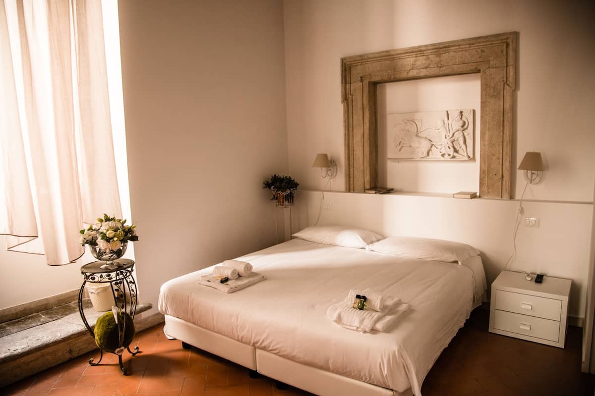 A neatly arranged bedroom with a bed, bedside tables, and a wall-mounted artwork.