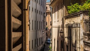 Una estrecha calle adoquinada bordeada por edificios históricos con balcones y una torre del reloj.