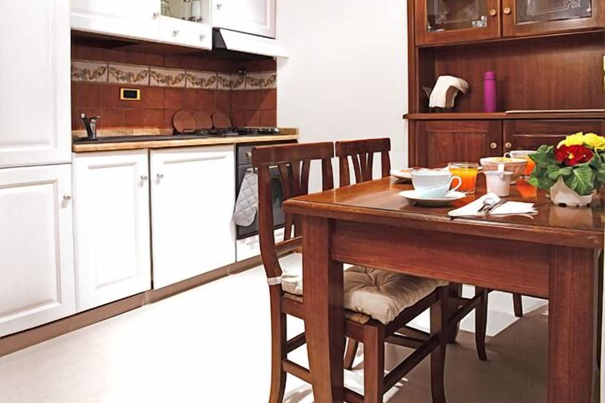 A kitchen with white cabinets, a wooden dining table, and a breakfast setting.
