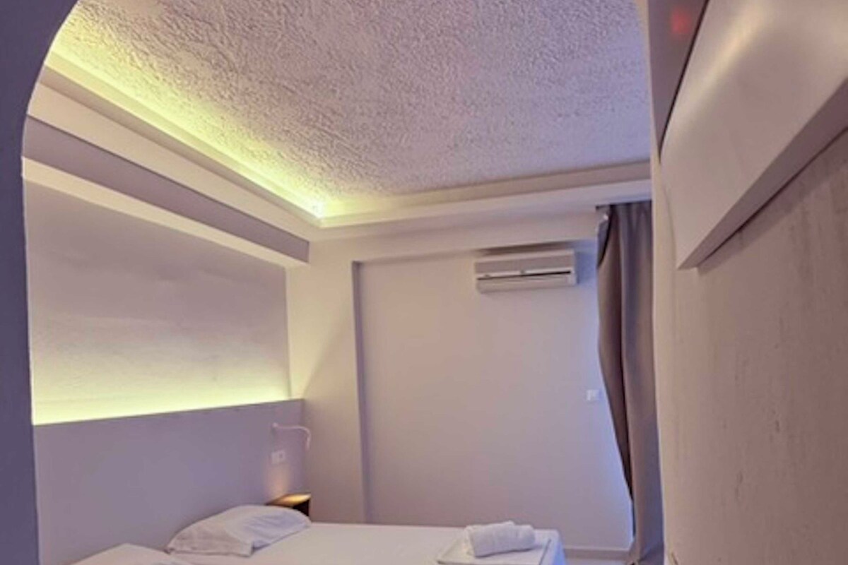 A modern bedroom with a large bed, an arched doorway, and a built-in wardrobe.