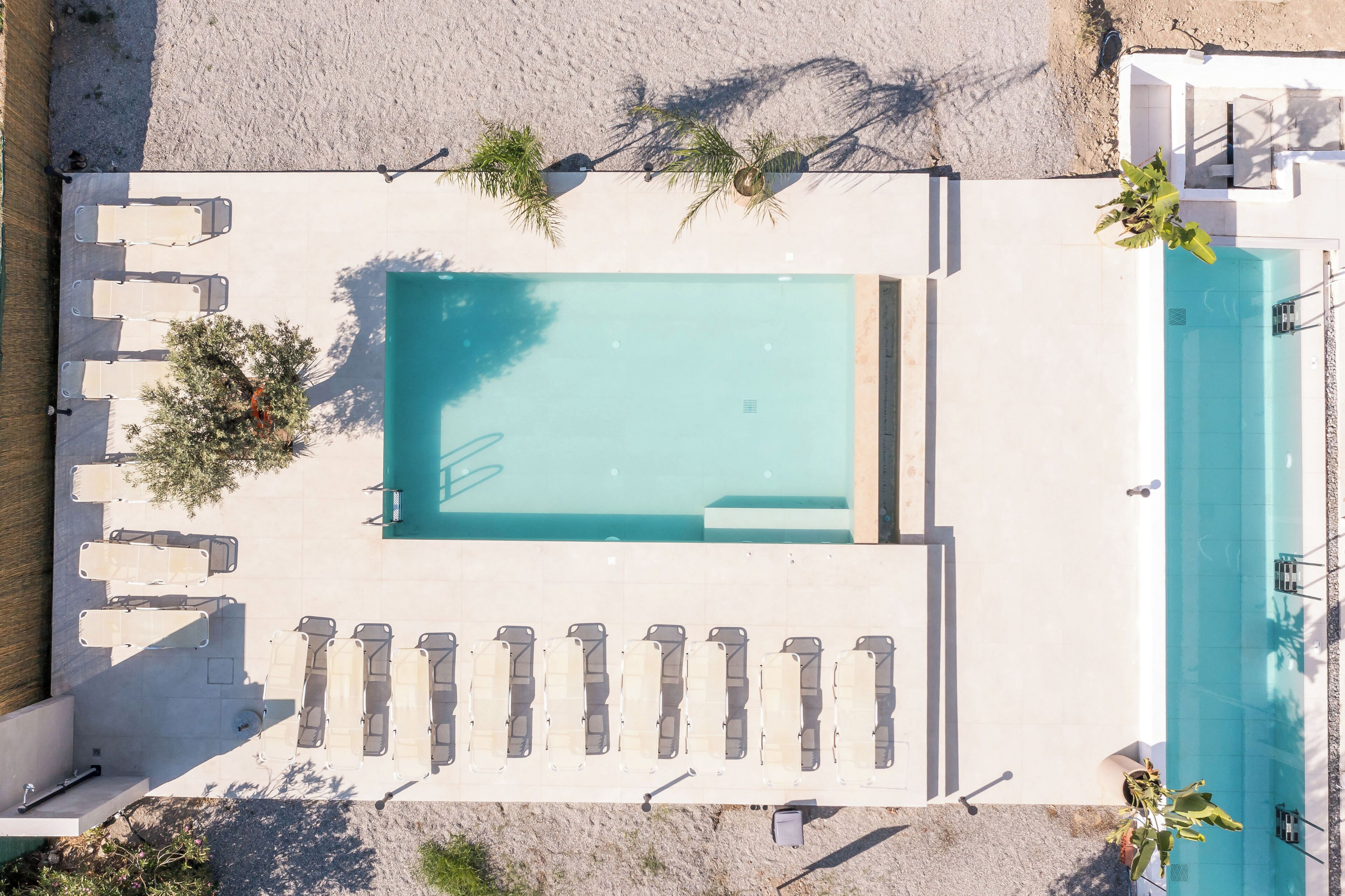 Vista aérea de un área de piscina con sillones de descanso y una pequeña terraza.