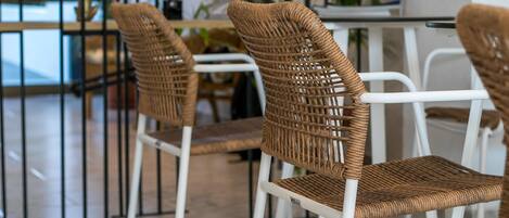 A dining area with wicker chairs and a white table.
