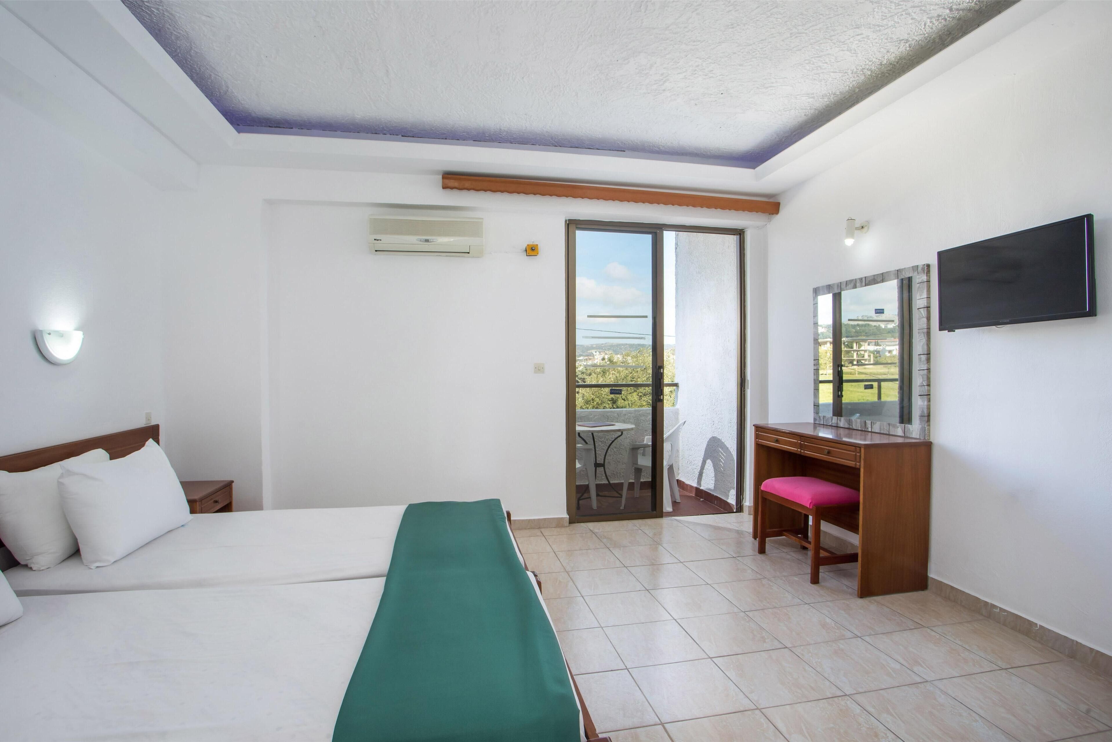 Une chambre d’hôtel avec un lit, un bureau, une chaise, une télévision et un balcon avec vue.