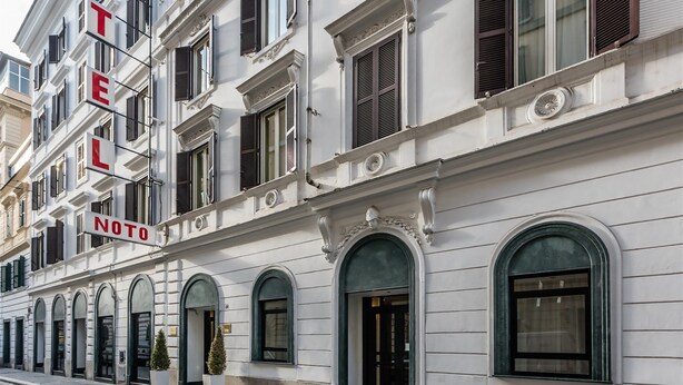 A multi-story hotel with a classic architectural style, featuring arched windows and decorative moldings. - Raeli Hotel Noto (Rome)