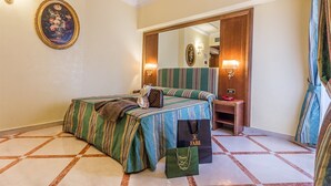 A hotel room with a bed, a mirror, a green-striped bedspread, a handbag, and a shopping bag. - Raeli Hotel Noto (Rome)
