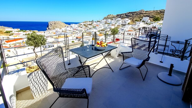 Ein Balkon mit zwei Stühlen, einem Tisch und einer Obstschale.