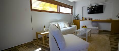 A modern living room with a white sofa, a coffee table, and a TV mounted on the wall.