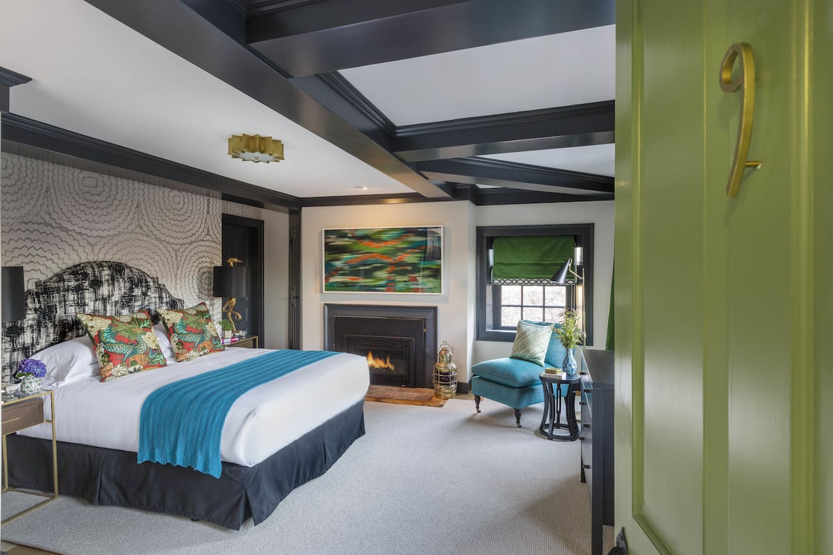Une chambre à coucher moderne avec un grand lit, une cheminée et une vue sur l’extérieur.