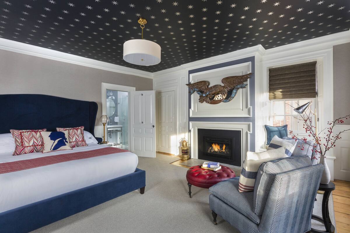 Une chambre à coucher avec un grand lit, une cheminée et un plafond décoré de motifs en forme d’étoiles.