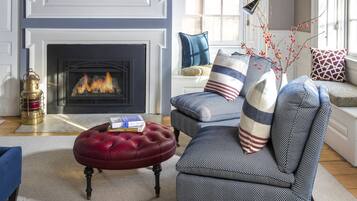 Una sala de estar con chimenea, un otoman rojo, un sillón azul y un techo decorativo con motivos de estrellas.
