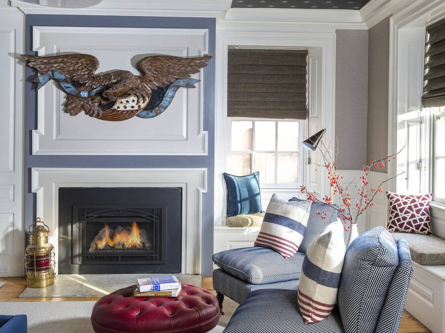 Una sala de estar con chimenea, un otoman rojo, un sillón azul y un techo decorativo con motivos de estrellas.