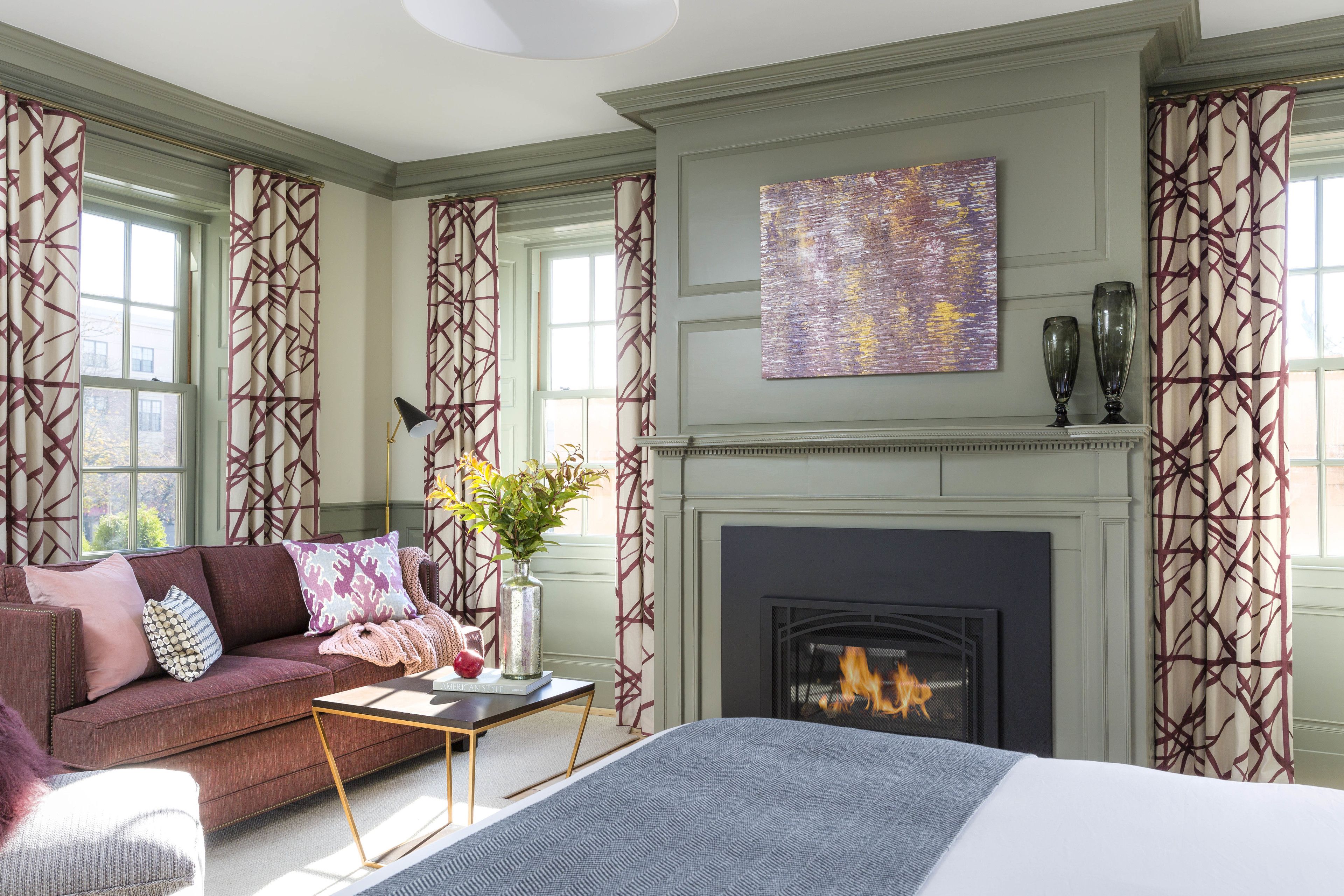 A room with a fireplace, a sofa, a bed, and a table with a vase of flowers.