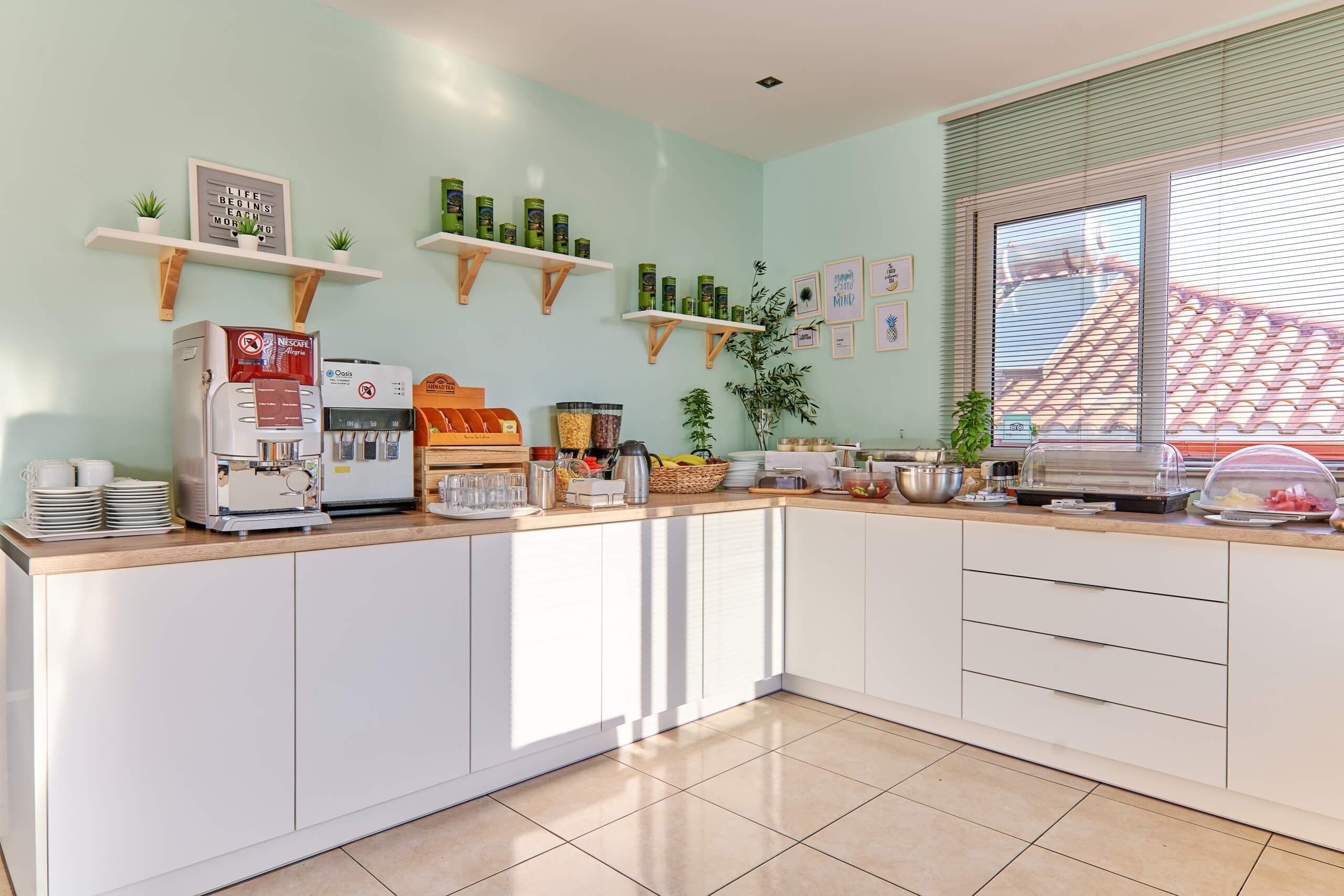 A modern kitchen with a coffee machine, tea station, and various food items on the counter.