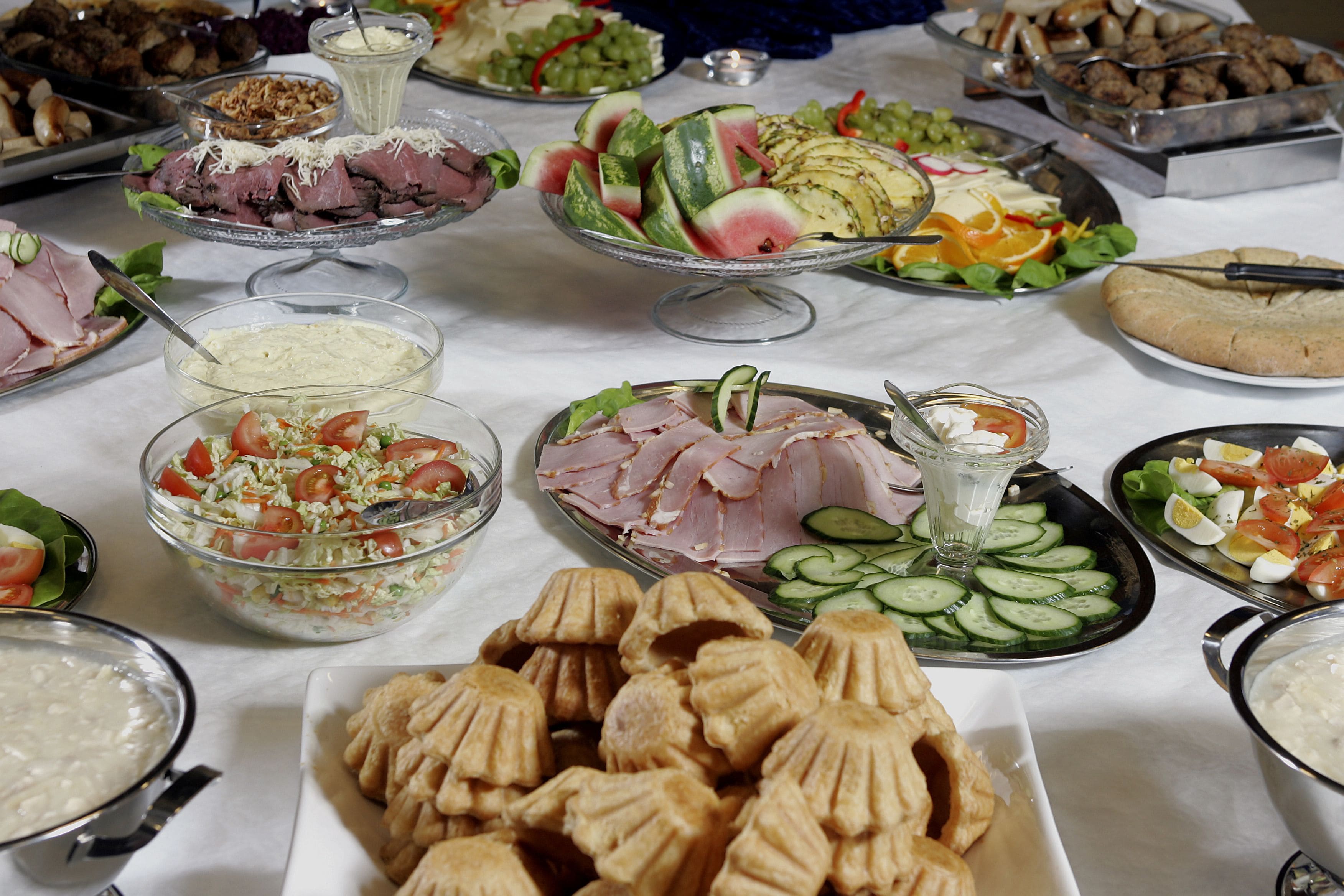 En buffet med forskellige retter, herunder salater, kød og grøntsager.