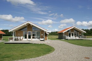 Two modern cabins with large windows and a covered patio area. Each cabin has a set of outdoor furniture.