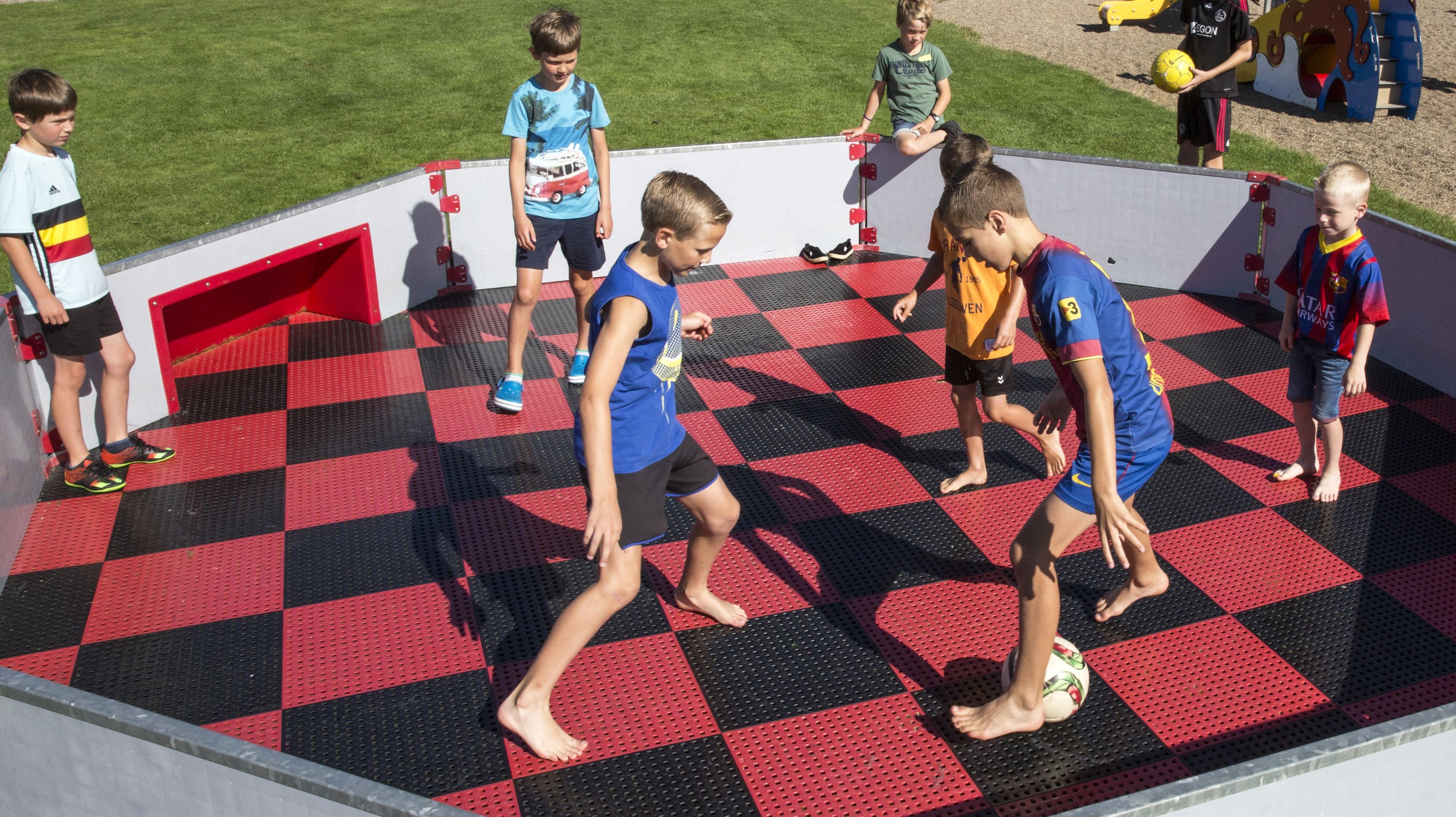 A group of children playing on a checkered floor with a red and black pattern.
