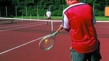 Una cancha de tenis con una red en el centro, rodeada por una valla.