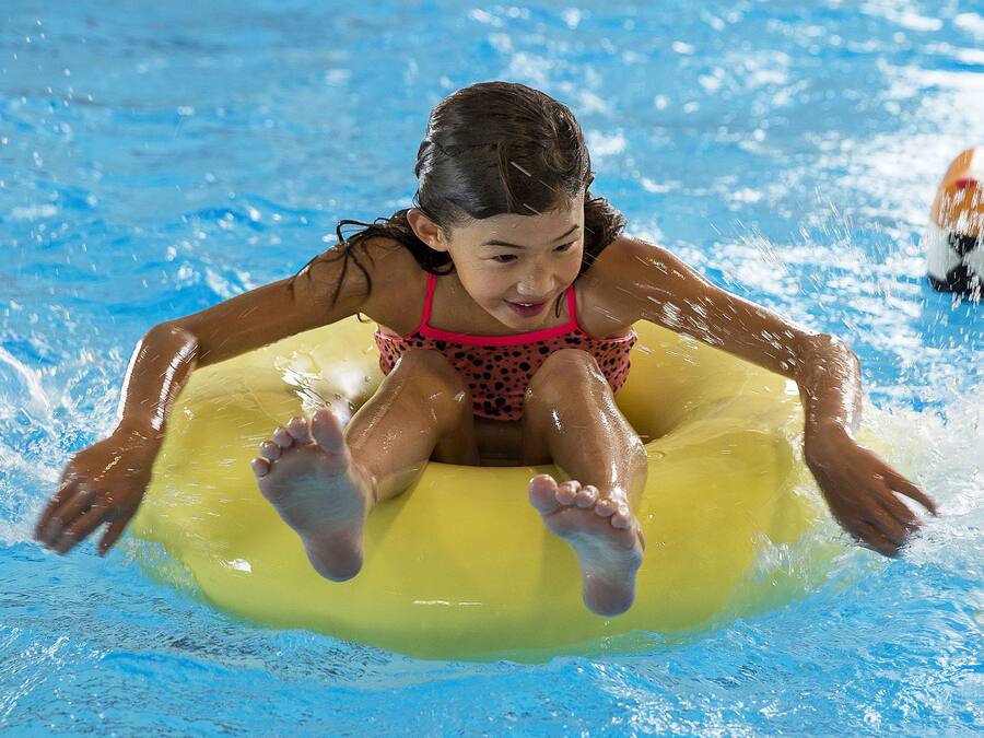 A person floating on a yellow inner tube in a pool.
