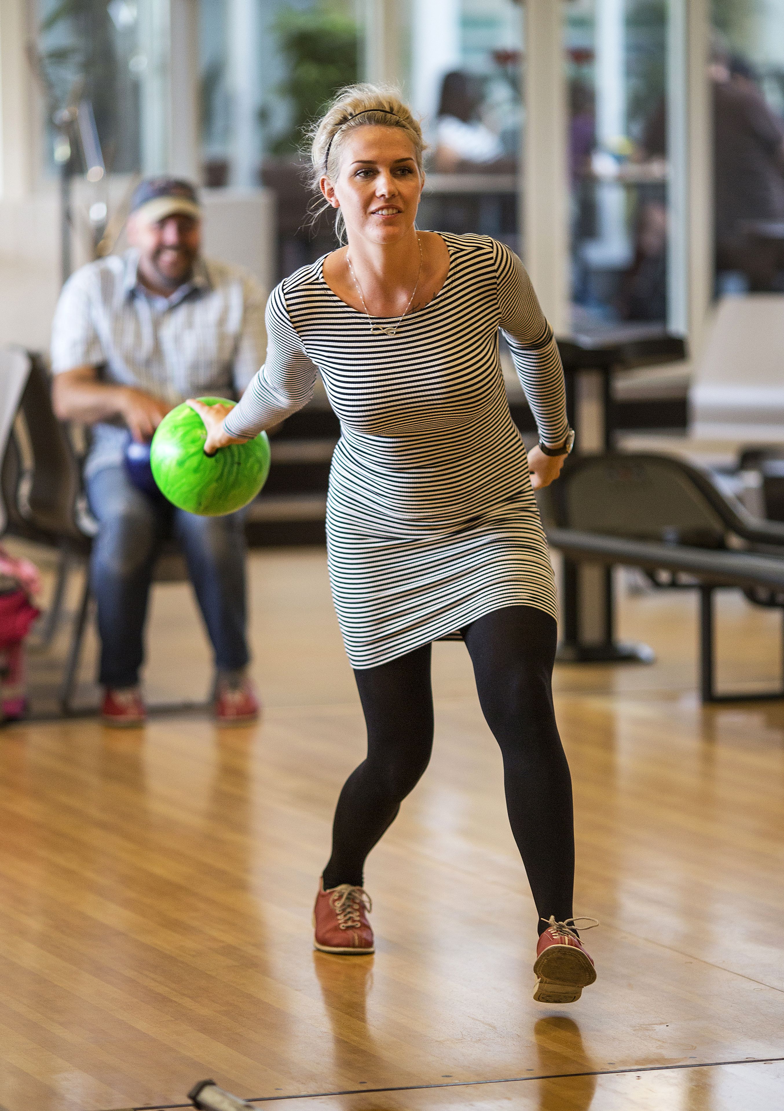 A person in a striped dress holding a bowling ball in a bowling alley.