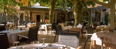 An outdoor dining area with round tables, chairs, and umbrellas.