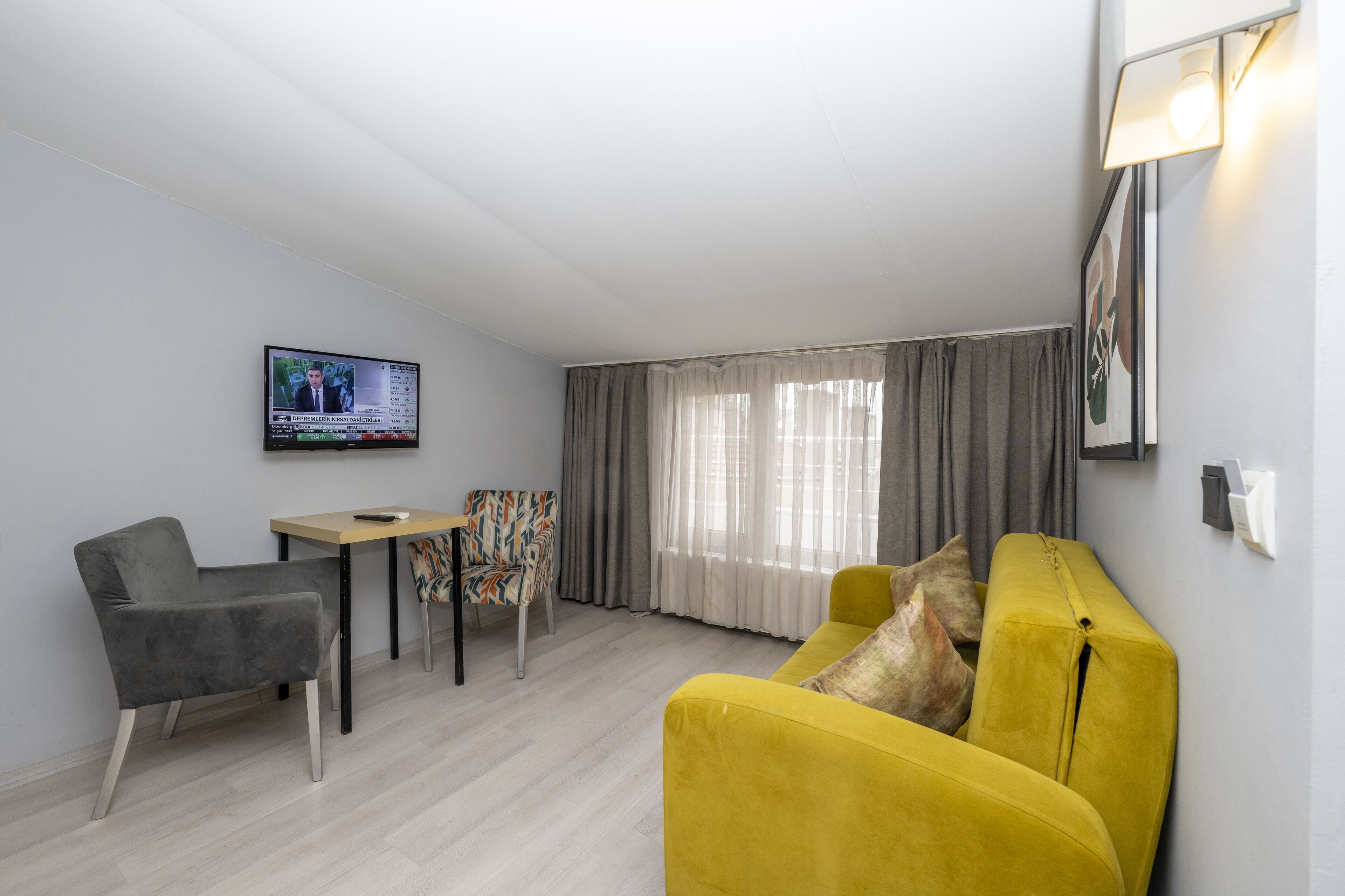A modern living room with a sofa, a chair, a small table, and a TV mounted on the wall.