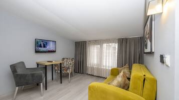 A modern living room with a sofa, a chair, a small table, and a TV mounted on the wall.
