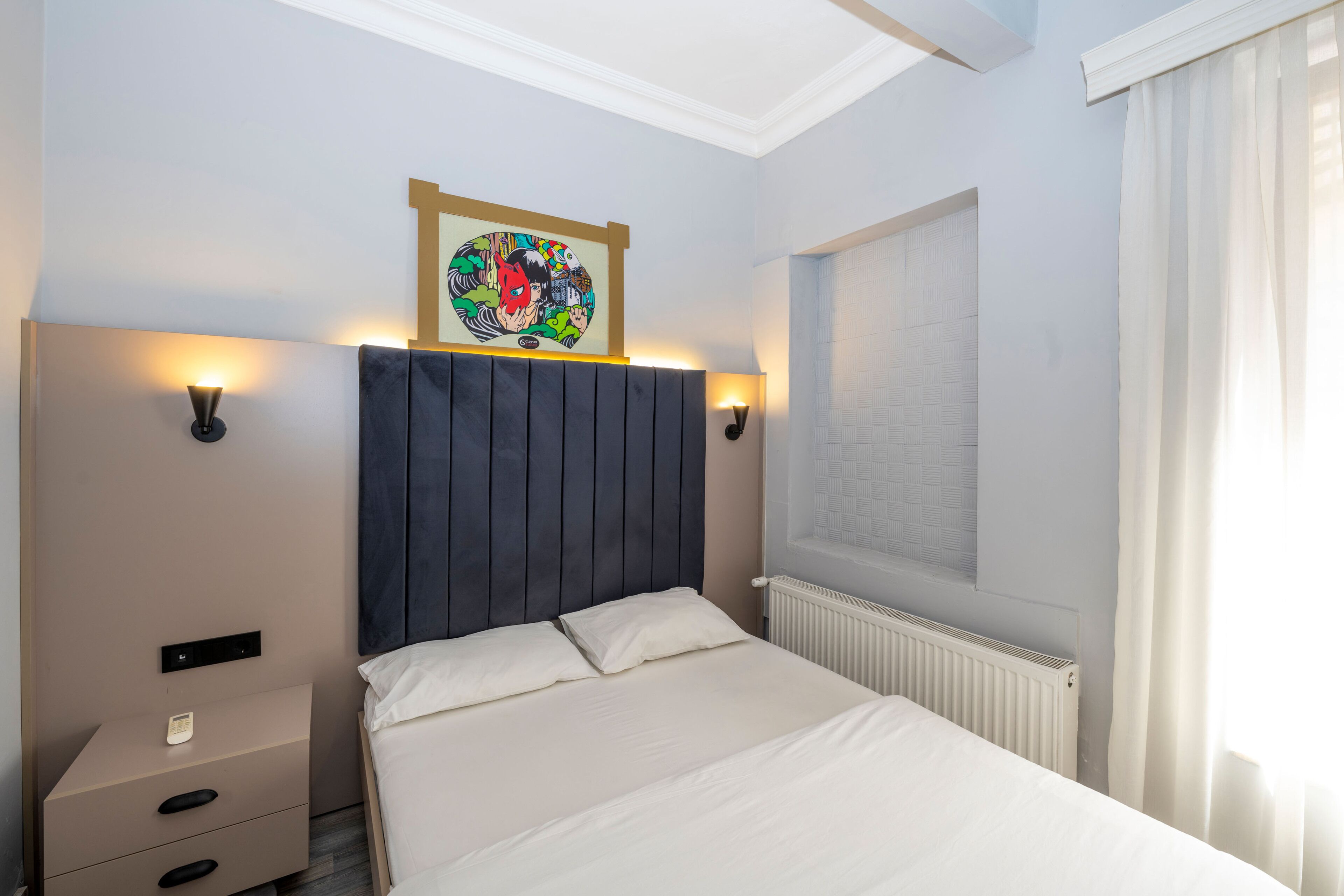 Une chambre à coucher bien rangée, avec un lit, des tables de chevet et des appliques murales.