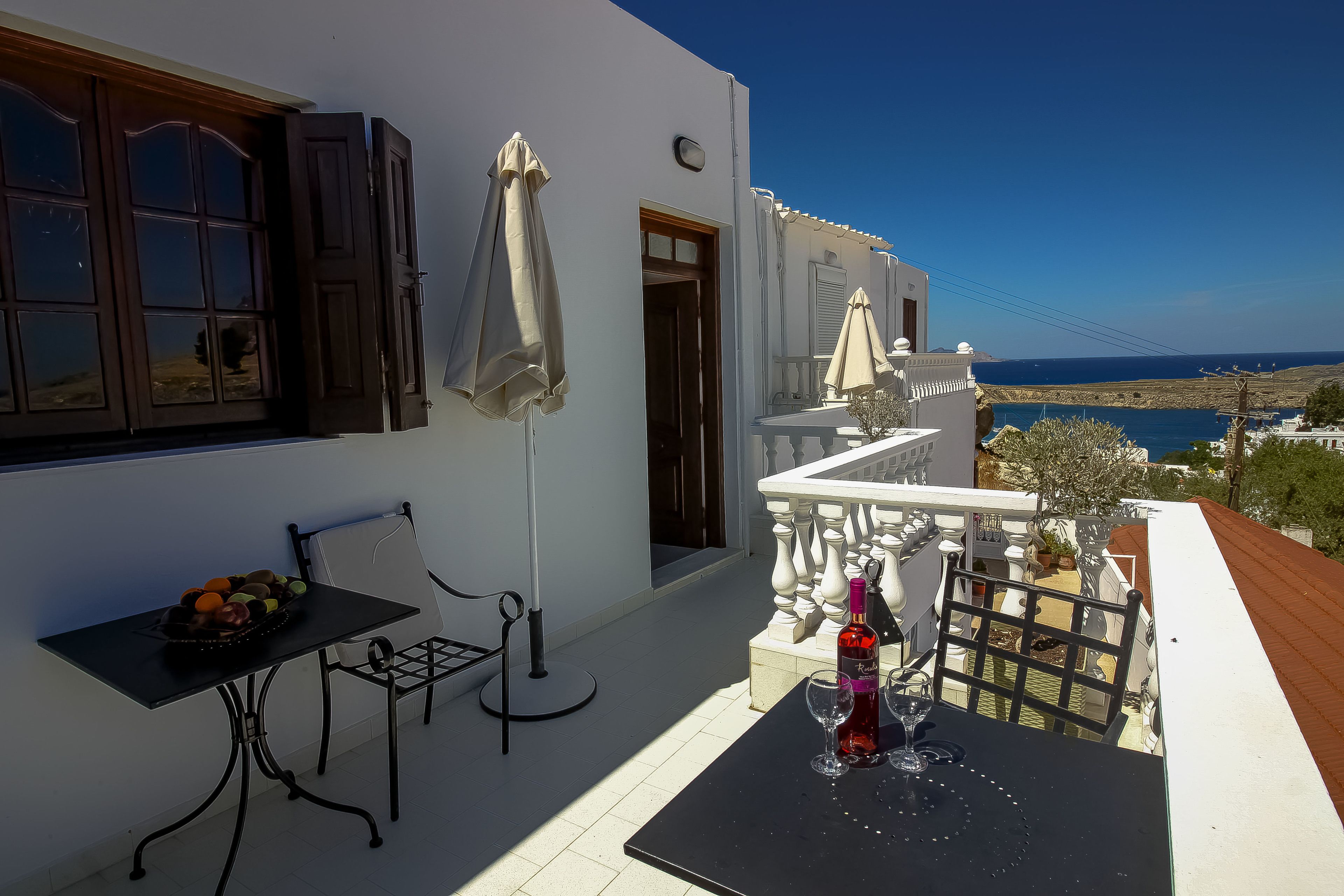 A balcony with a table, chairs, and a bottle of wine.