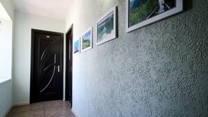 A hallway with a textured wall, a door with a unique design, and framed pictures. - Hotel Kutaisi Globus (Kutaisi)