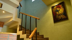 A staircase with wooden steps and a metal railing, leading to a room with a bed and a painting on the wall. - Hotel Kutaisi Globus (Kutaisi)