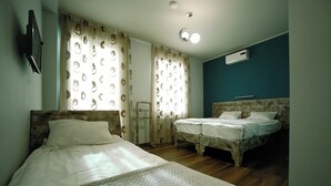 A bedroom with two beds, wooden headboards, a mirror, and a ceiling light fixture. - Hotel Kutaisi Globus (Kutaisi)