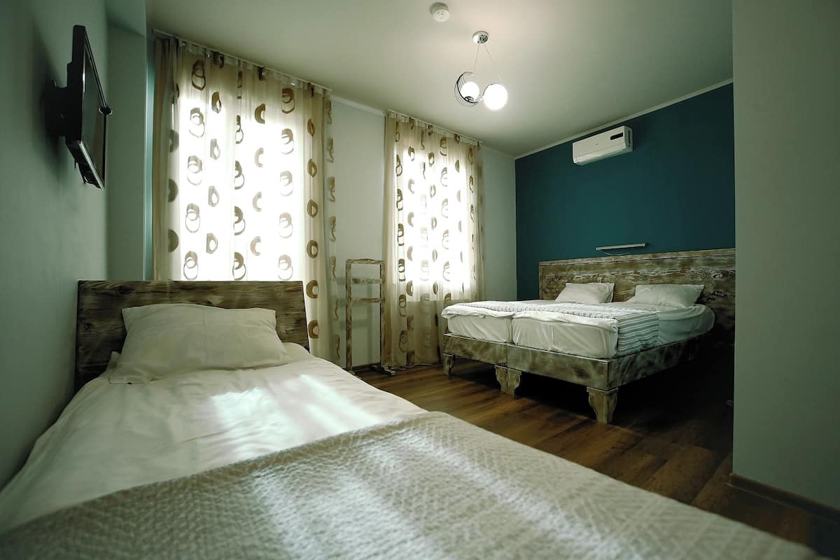 A bedroom with two beds, wooden headboards, a mirror, and a ceiling light fixture.