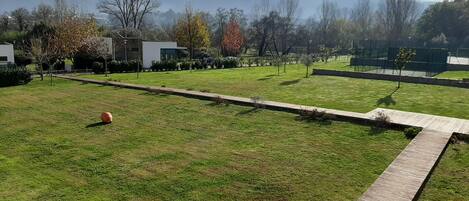 A grassy area with a pathway, trees, and a building in the background.