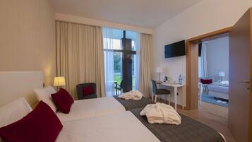 Habitación de hotel con dos camas, un escritorio, una silla, un televisor y vistas al exterior.