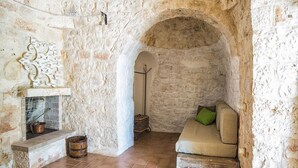 Una habitación de paredes de piedra con chimenea, un sofá y un banco de madera rústica.