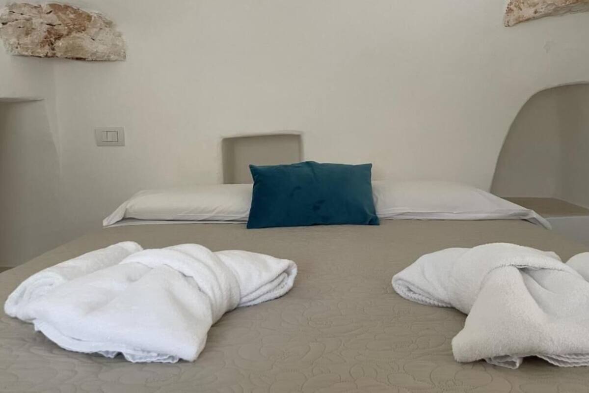 A hotel room with a bed, two pillows, and two towels.