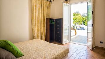 Un dormitorio con una cama, un armario y un ventanal corredero que da a un patio.