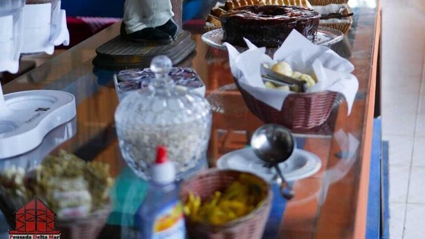 A buffet setup with various food items and a statue of a person. - Delta Mar Maresias (São Sebastião)
