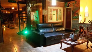 A cozy living room with a black leather sofa, a wooden coffee table, and a mural on the wall. - Delta Mar Maresias (São Sebastião)