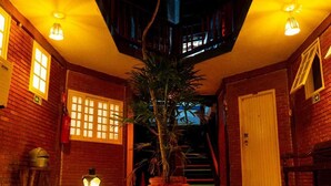 A spacious indoor area with a central plant, a staircase, and a door. - Delta Mar Maresias (São Sebastião)